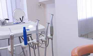 The image shows an interior dental office setting with various pieces of equipment, including a dental chair, dental instruments, and a sink.