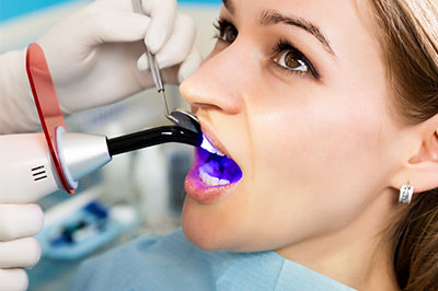 Woman undergoing dental procedure with dentist using a dental mirror and suction device.