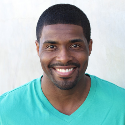 A man and woman pose closely together, smiling, with the man s arm around the woman, both appear elderly and are outdoors during daylight.