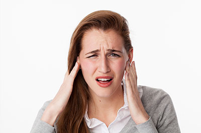 The image shows a woman with her hand on her head, appearing to be in disbelief or concern, set against a white background.