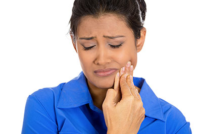 A woman with her eyes closed, holding her nose, possibly indicating discomfort or pain.