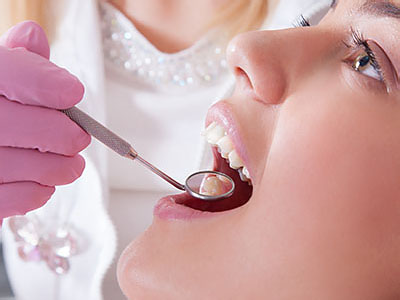 A dental professional is performing oral care on a patient using dental tools.